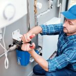 young-man-in-workwear-using-pliers-while-installing-water-filtration-system.jpg